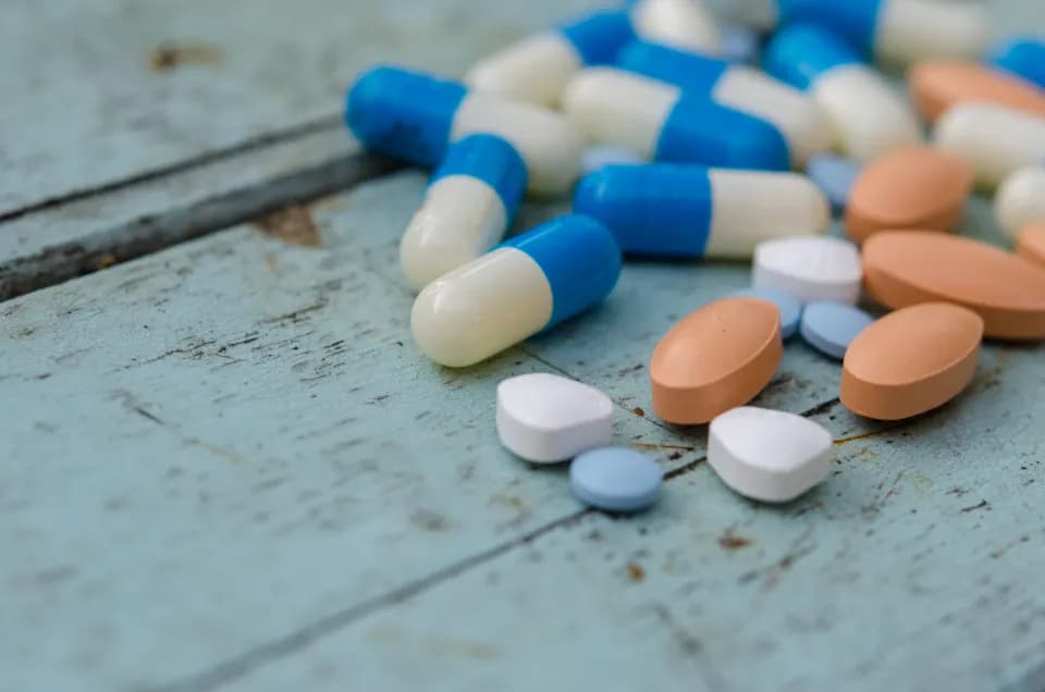Tablets and capsules on a pale blue wooden surface
